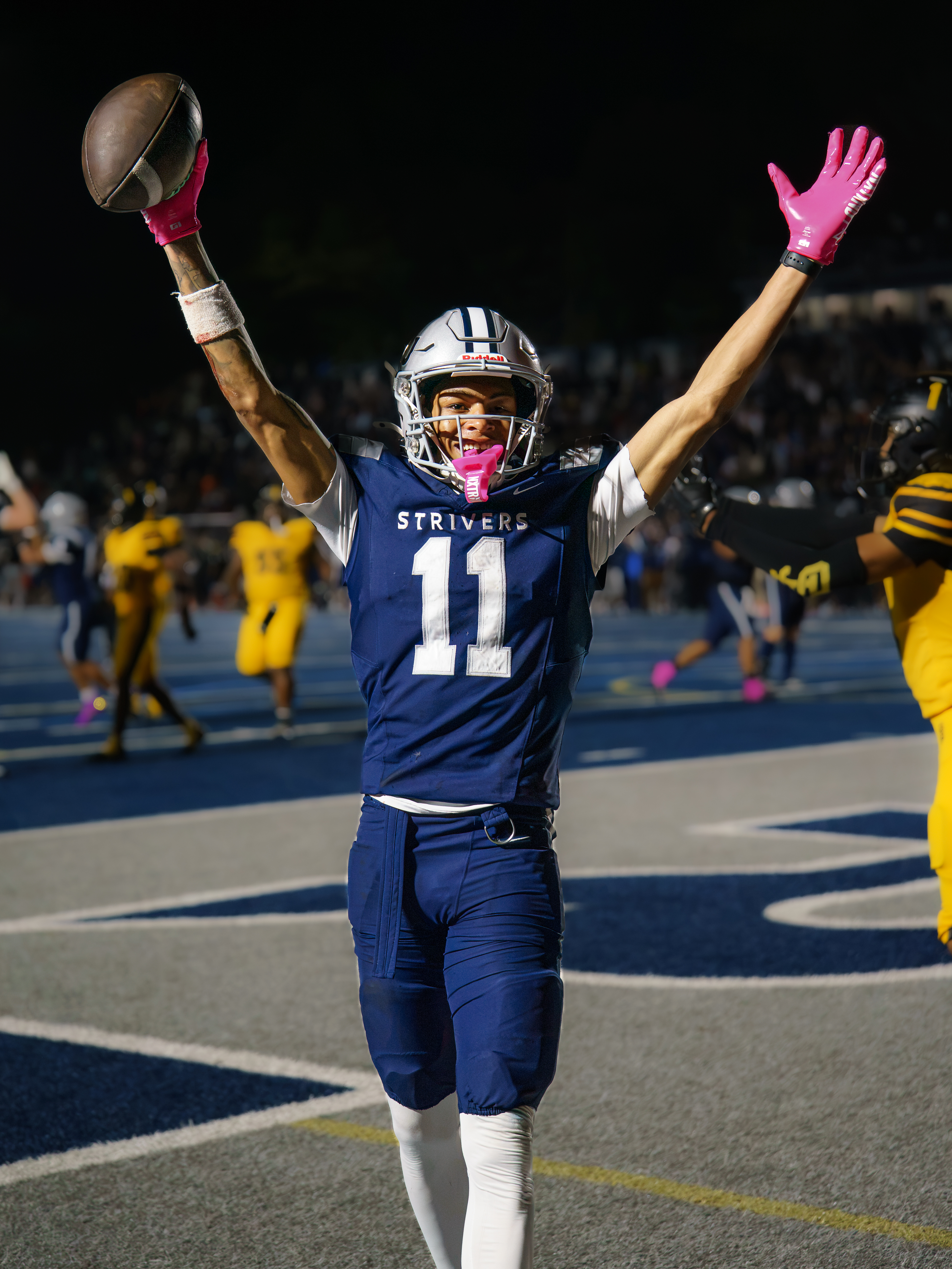 Vincent Hill Jr., No. 11 for The St. James, raises a football with both arms raised during the October 10 game against St. Frances.
